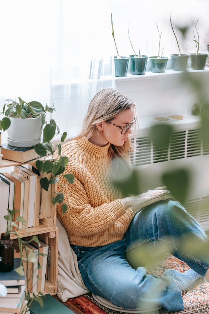 Woman reading beside houseplants creating a serene indoor atmosphere.